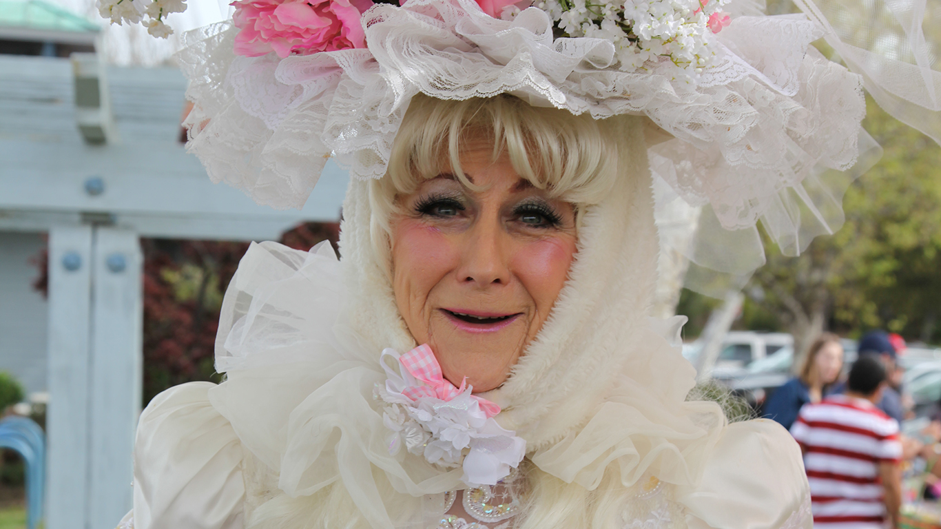 A woman in a elegant dress with a flower hat.