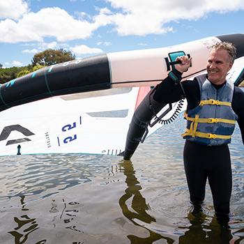 A man bring a wingfoil wing into the water.